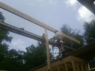 Carpenter setting a ridge beam over a new addition frame — Ice Dam Removal by Roofing Brothers in Wales