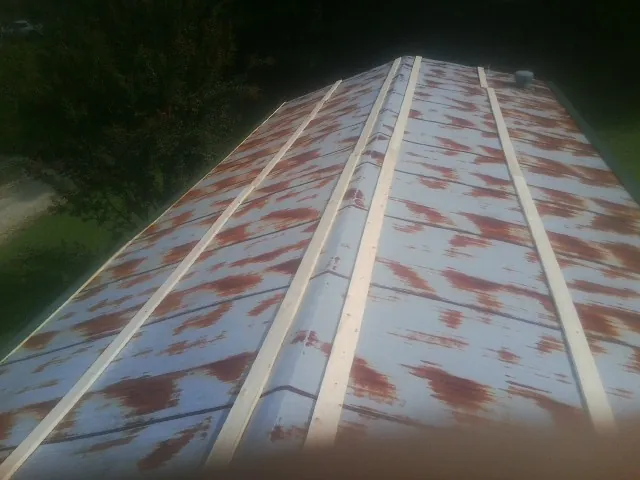 Rusted metal roof panels with new wood purlins before replacement — Storm Damage Roof Repair in Wales by Roofing Brothers