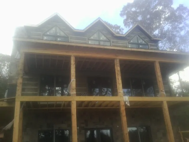 Dormers and porch framing on a large log home under construction — Roof Coating work by our crew in Wales