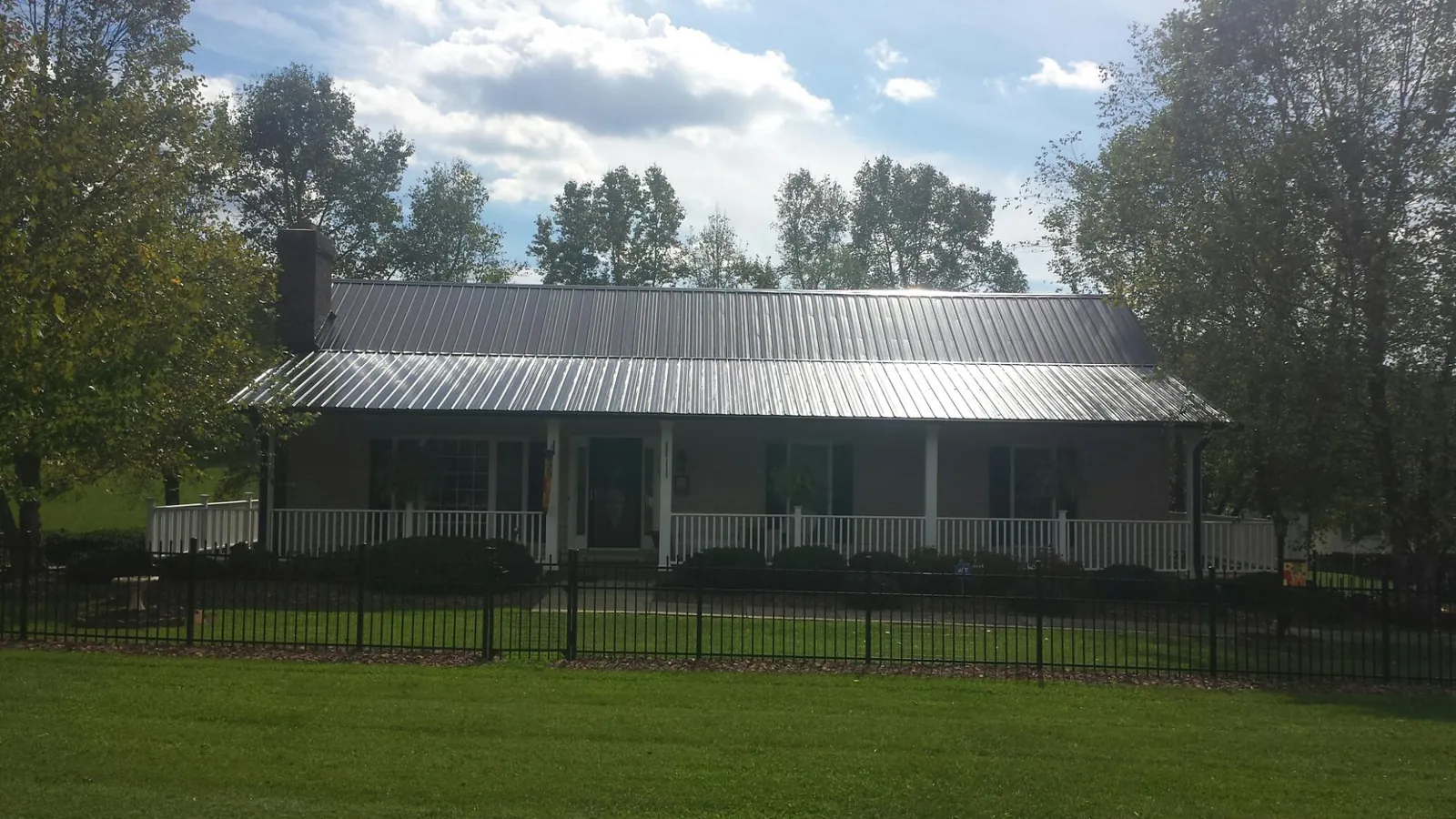 Gray metal roof on a brick ranch with a full width front porch — Gutter Guard Installation work by our crew in Wales